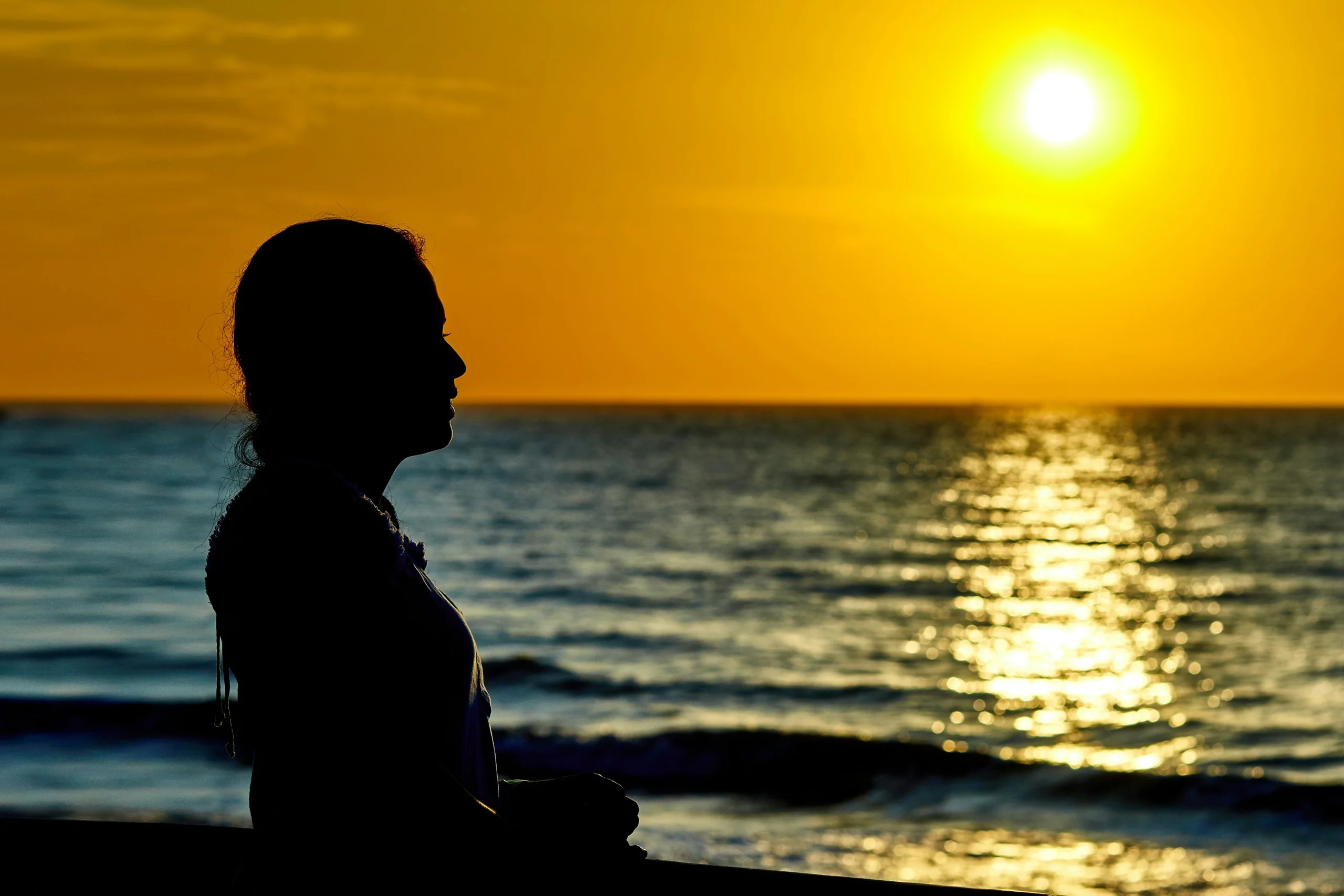 Silhouette of a woman meditating at sunset, symbolizing healing and therapeutic support for bipolar depression.
