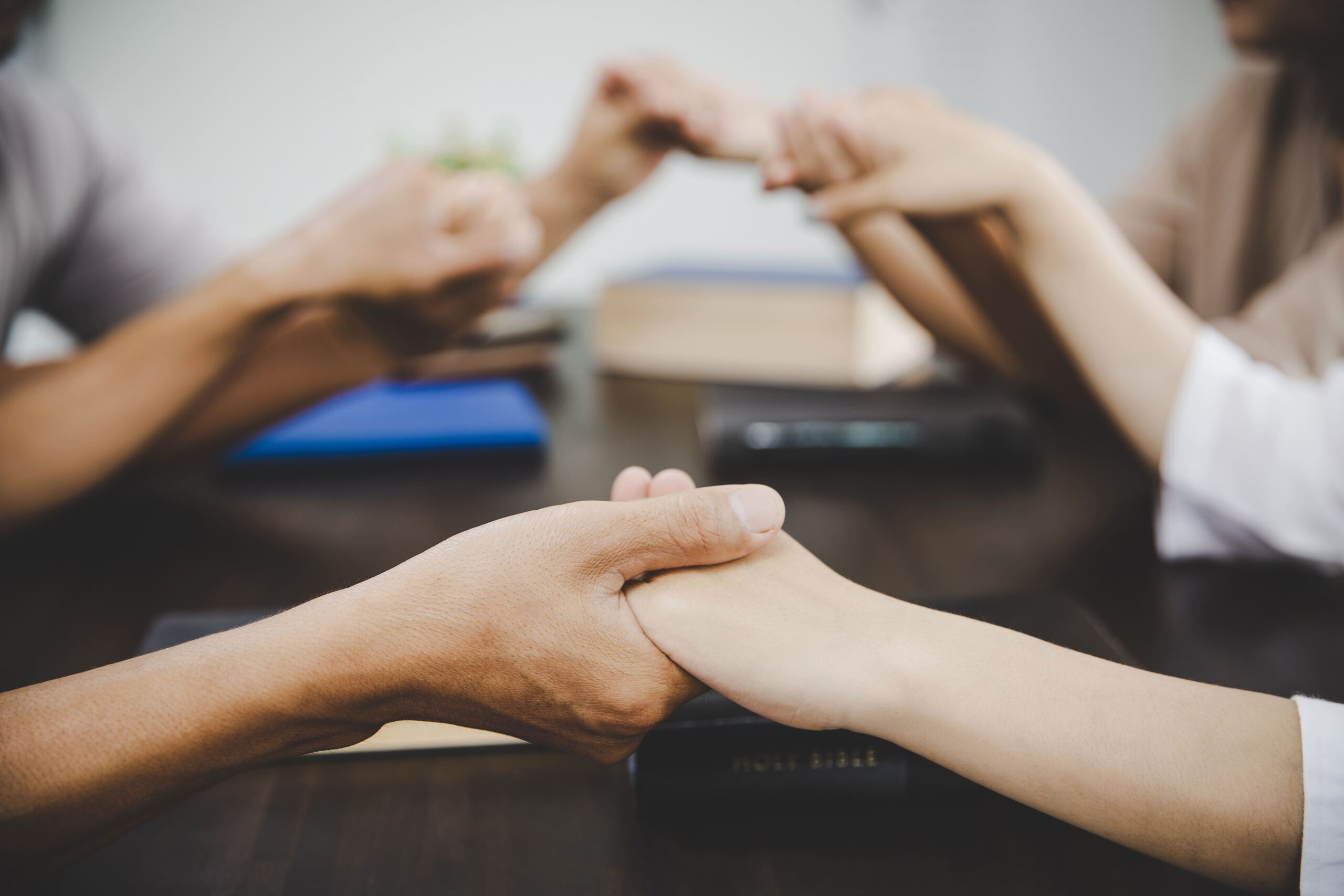 Group holding hands in prayer, symbolizing support and therapeutic integration.